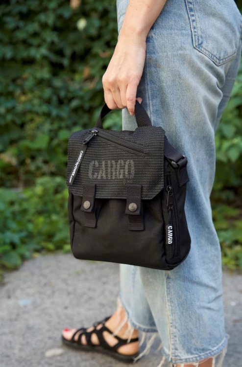 kobieta z odblaskową czarną listonoszką mini plecak z cordury cargo by owee na tle roślin