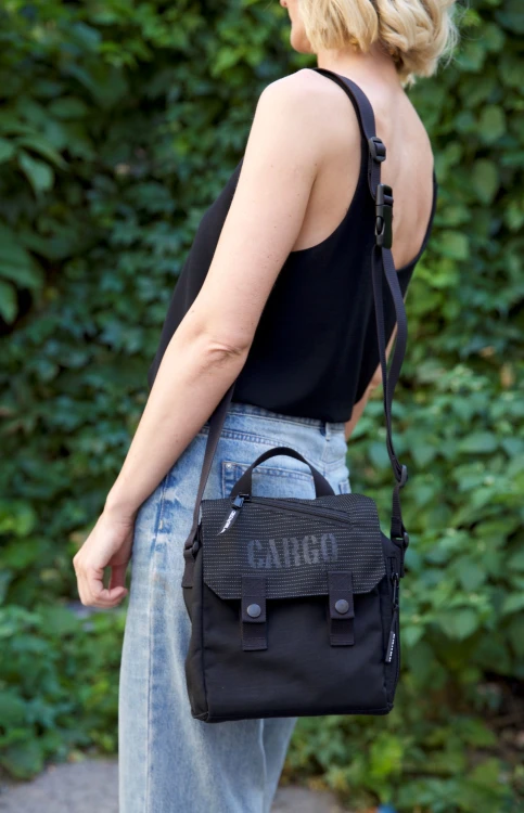 kobieta z elegancką odblaskową czarną listonoszką mini plecak z cordury cargo by owee na tle roślin