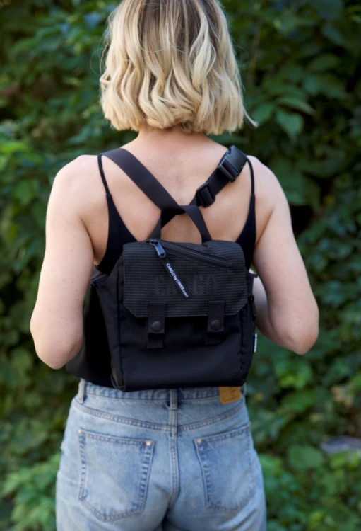 kobieta ze stylową odblaskową czarną listonoszką mini plecak z cordury cargo by owee na tle roślin
