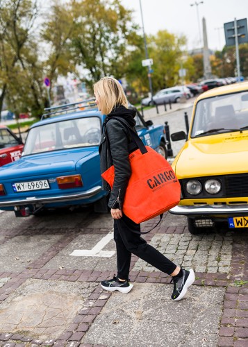 kobieta z pomarańczową pojemną wytrzymałą torbą miejską z cordury cargo by owee na tle miasta i samochodów