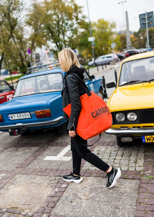 kobieta z pomarańczową pojemną wytrzymałą torbą miejską z cordury cargo by owee na tle miasta i samochodów