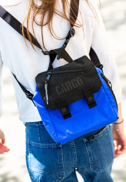 Torba mini-plecak Reflective royal blue noszona na ramieniu; obok czarny wariant